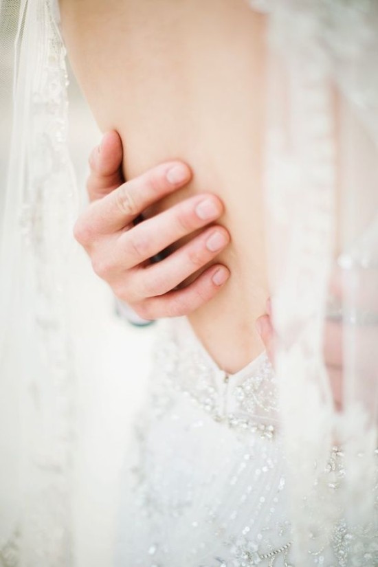 A groom tenderly holding the brides arm in her dress