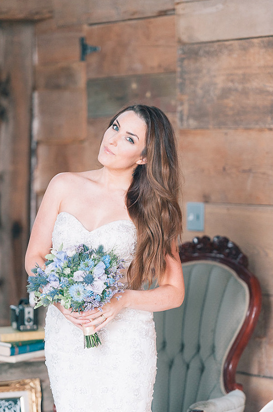 Beautiful bride in lace dress holding blue flower bouquet