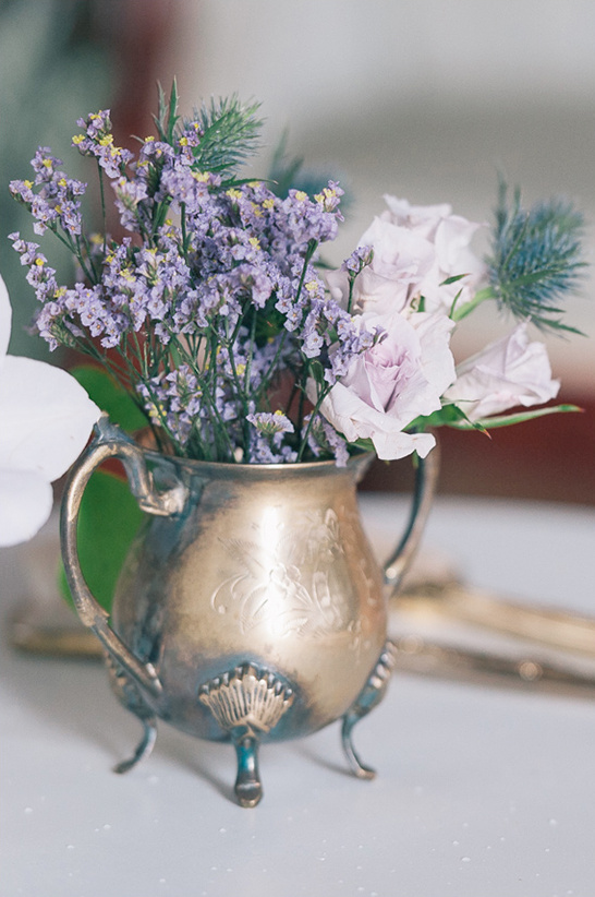 Antique silver creamer holding purple and white flowers