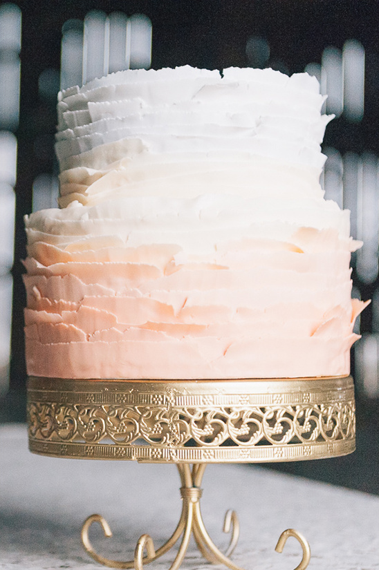 Ombre ruffled wedding cake on a golden pedestal stand