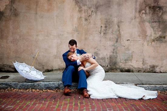 Bride and groom resting against old wall after wedding