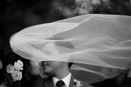 Black and white image of a bride and groom kissing
