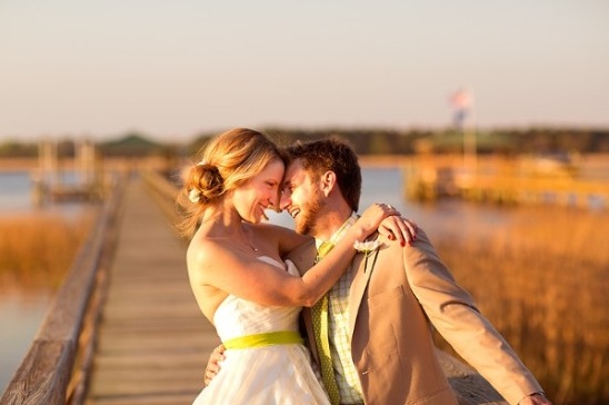 Happy bride and groom embrace romantically on a pier