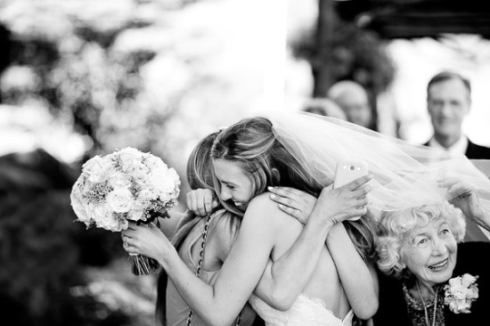 Bride embraces guest holding flowers at her wedding