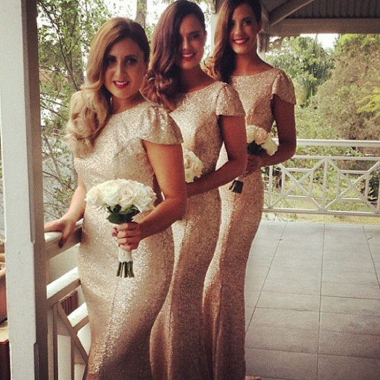 Bridesmaids in sparkly gold gowns hold white roses