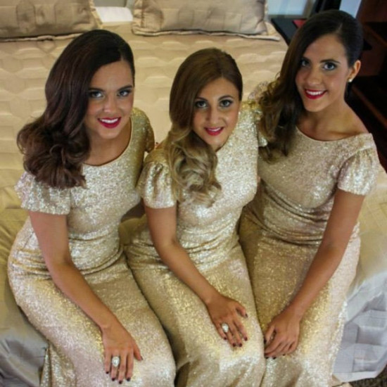 Three women in matching gold sequin dresses smiling