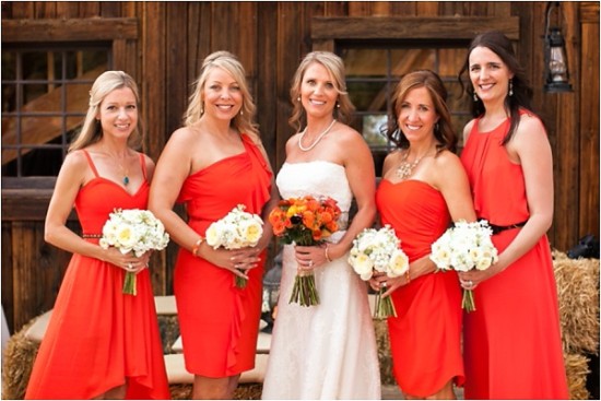 Smiling bride and bridesmaids in red dresses at barn wedding