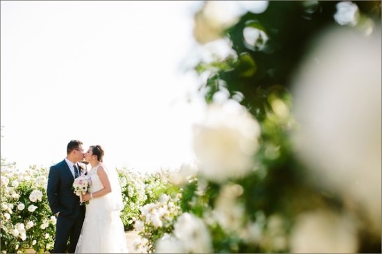 Loving couple share wedding kiss surrounded by white flowers