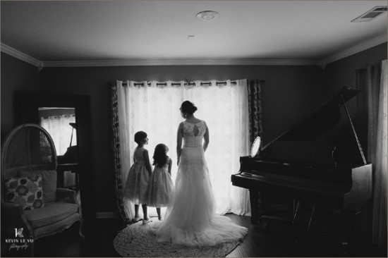 Bride and flower girls gazing out window in black and white