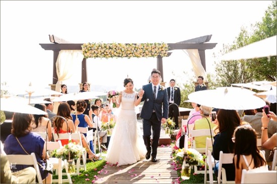 Happy couple walks aisle after outdoor wedding ceremony