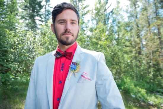 Stylish groom in light blue suit red shirt bow tie outdoors