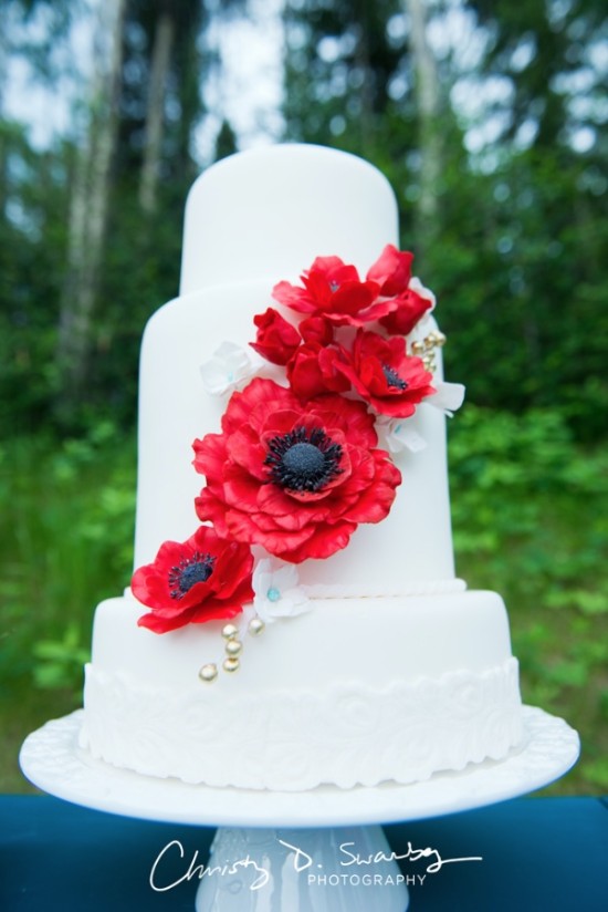 White wedding cake with red poppy flower decorations