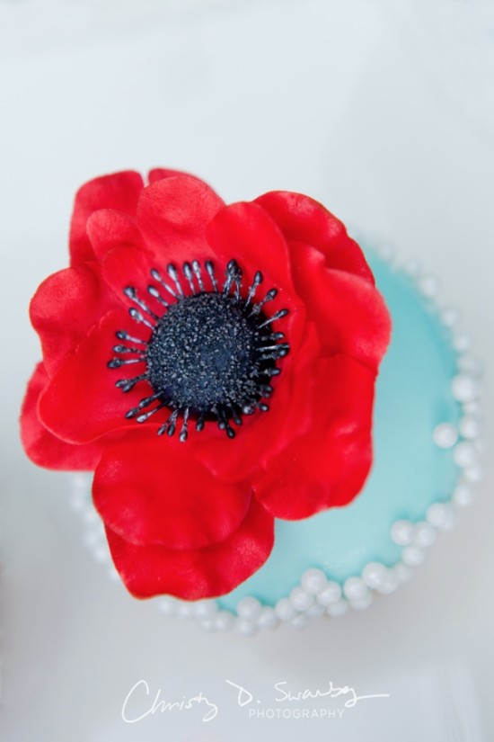 Red anemone flower on blue cupcake with pearl sprinkles