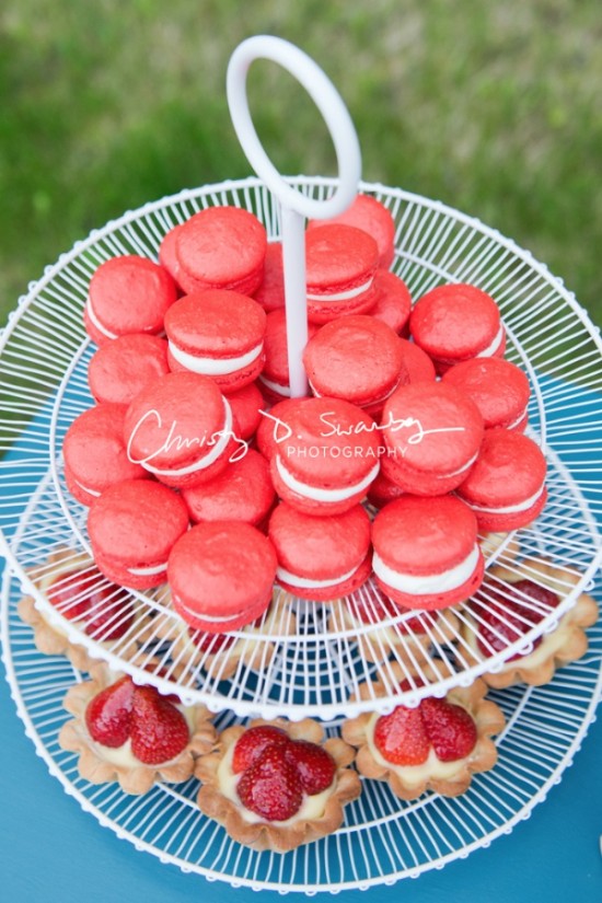 Dessert stand of red macarons and strawberry tarts