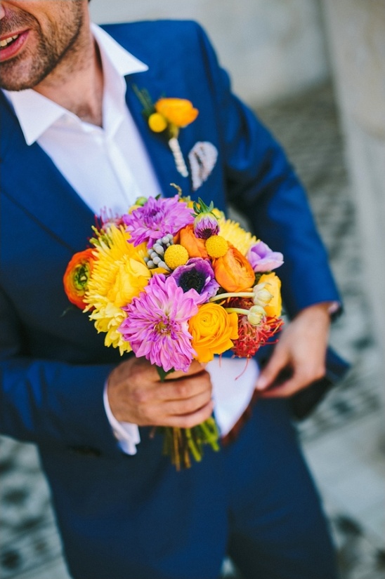Groom in blue suit holding vibrant colorful bouquet