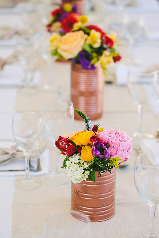 Colorful flowers in tin can vases on a table setting