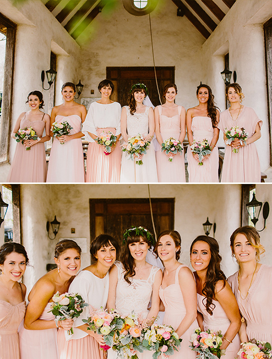 Bride and bridesmaids in pink dresses with bouquets pose outdoors