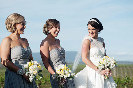 Bride and bridesmaids in gray dresses smiling at wedding