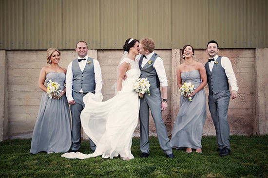 Wedding party posing in grey suits and dresses kissing