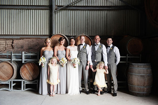 Wedding party poses by wine barrels at winery reception