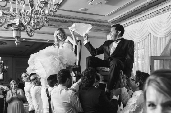 Black and white photo of bride and groom on chairs lifted