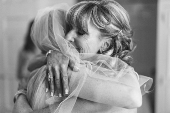 Mother of the bride embraces her daughter in black and white