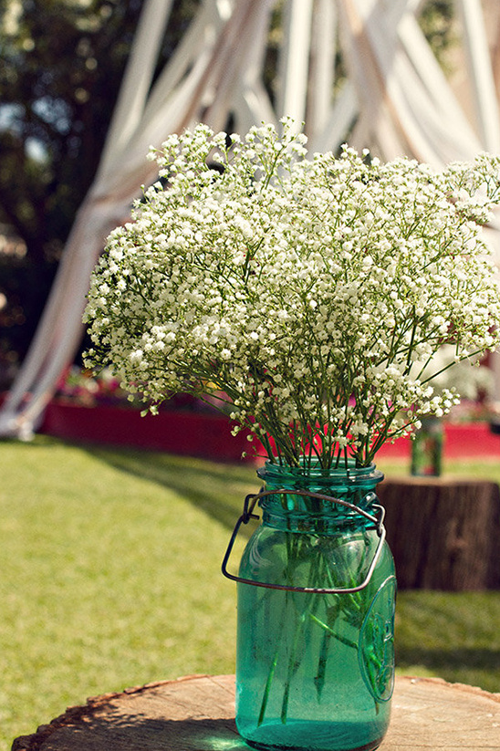 babys breath in mason jars decorate the wedding aisle