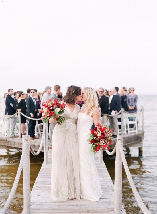 Two happy brides share a kiss at their wedding ceremony