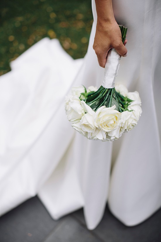 Bride holds white rose wedding bouquet at her wedding