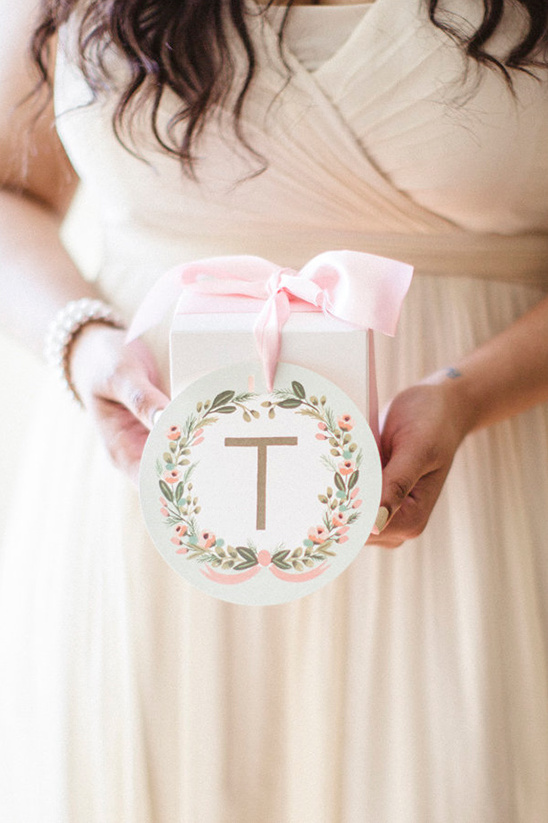 Bridesmaid holding a gift with initial T and pink ribbon