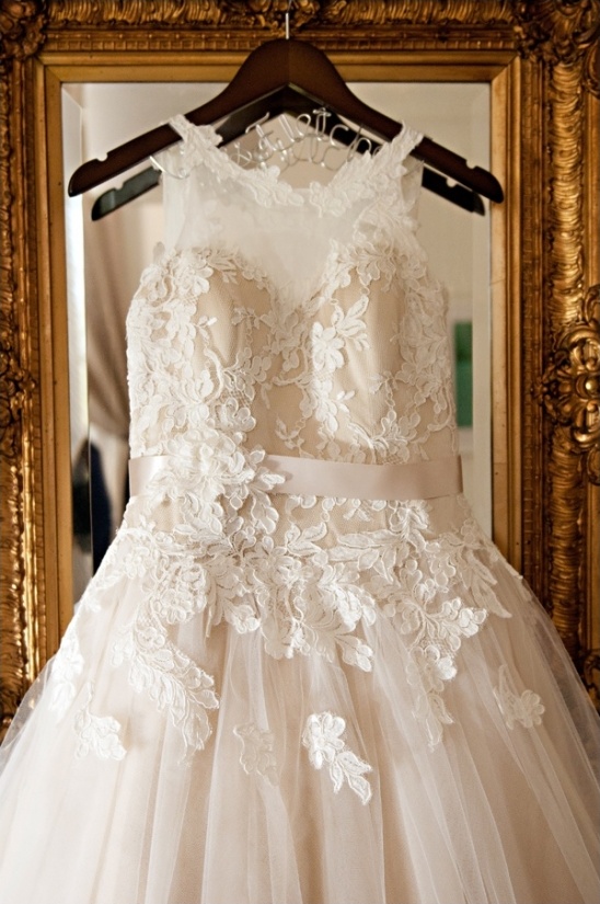 Elegant lace wedding dress on hanger in golden frame