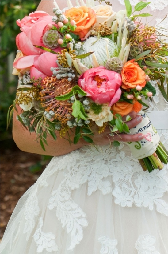 Bride with pink and orange bouquet in lace wedding dress