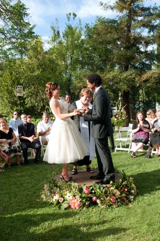 Bride and groom exchange rings at outdoor garden wedding