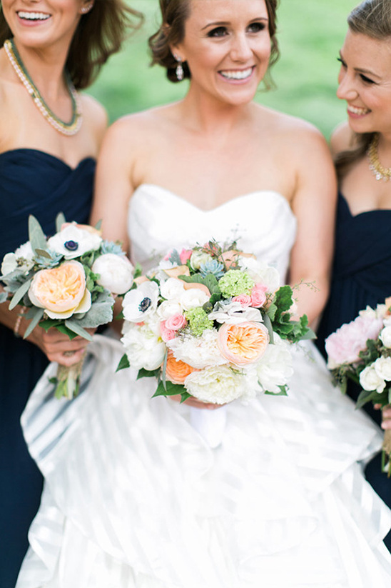Bride with bridesmaids in navy holding wedding bouquets