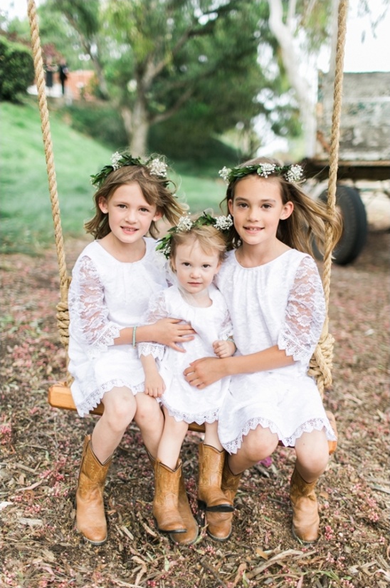 Three flower girls in white dresses on a rope swing