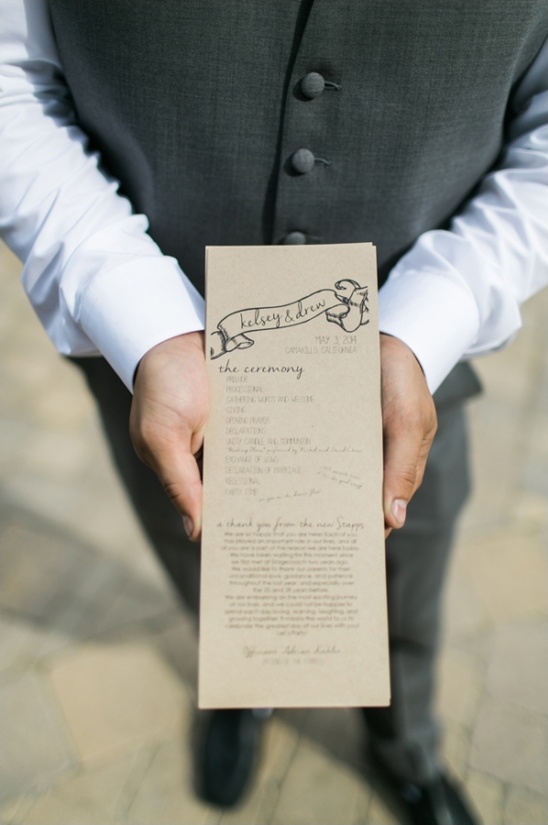 Groom holds wedding ceremony program for Kelsey and Drew
