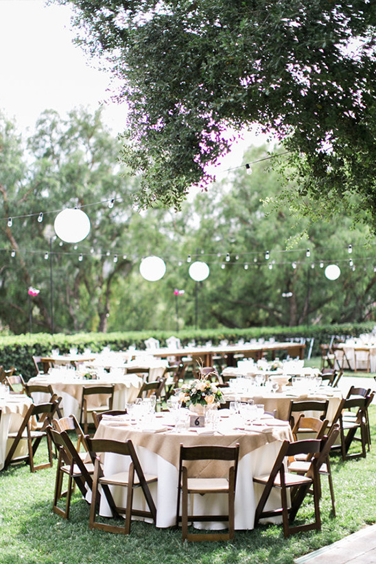 Outdoor wedding reception with round tables and string lights