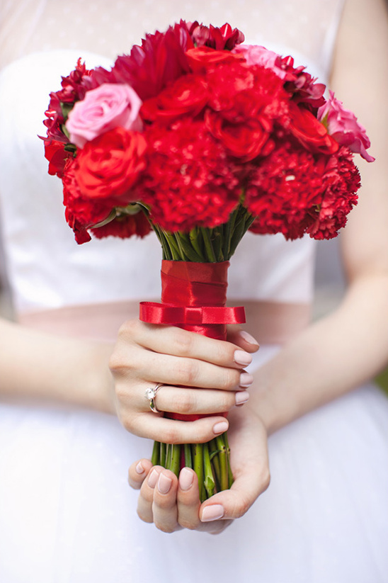 Bride holding red roses and pink carnations bouquet