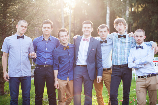 Groomsmen group in bow ties smiling at outdoor wedding
