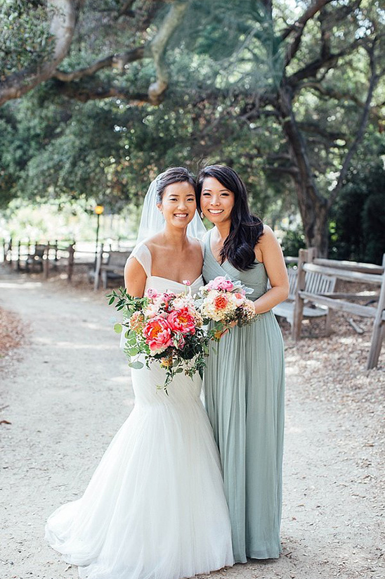 Bride and bridesmaid with bouquets in outdoor wedding