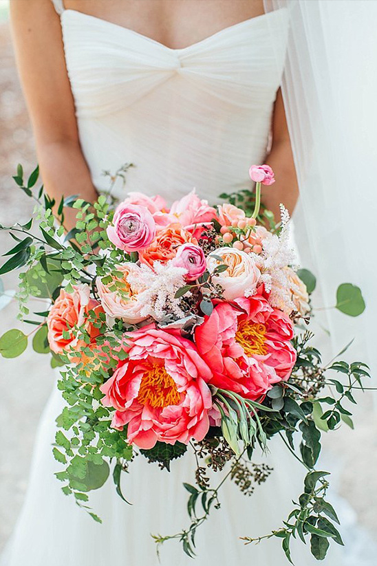 Bride holding a vibrant coral and pink peony bouquet