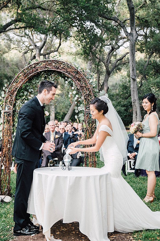 Bride and groom at outdoor wedding ceremony mixing sand