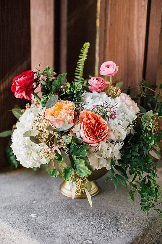 Elegant floral arrangement in gold vase with varied blooms