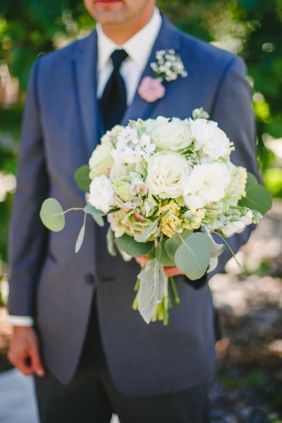Groom holds white rose bouquet wedding suit tie boutonniere