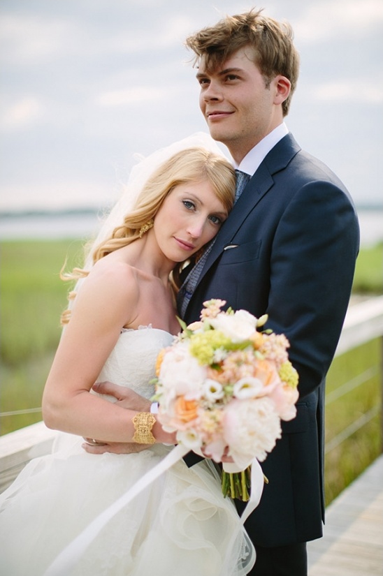 Bride and groom embrace holding flowers on wedding day