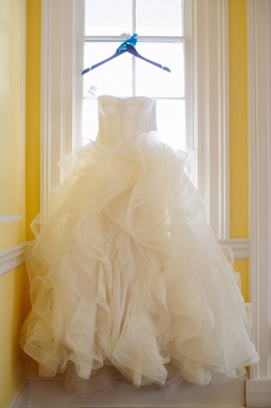 Ivory strapless wedding dress hangs in bright window