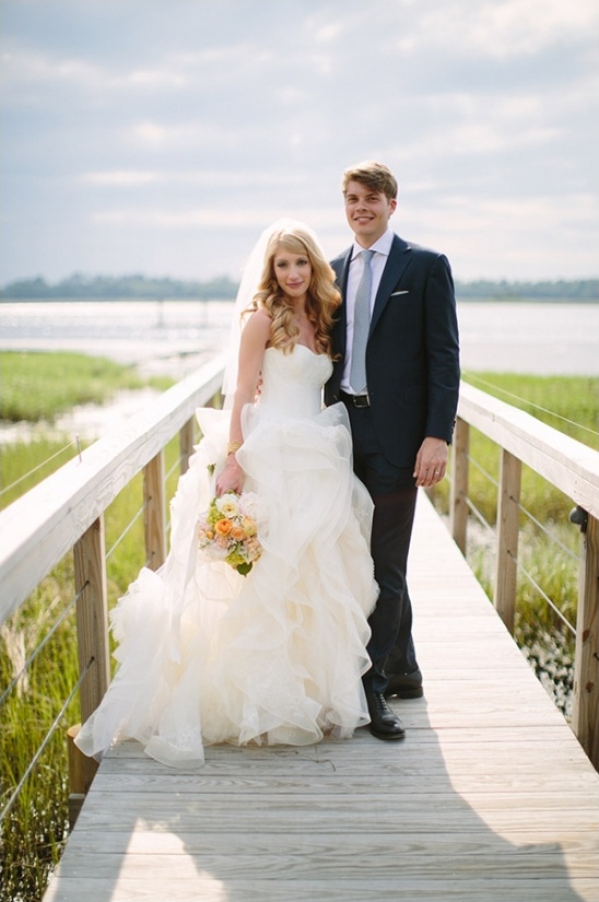 Bride and groom pose on a boardwalk at their wedding