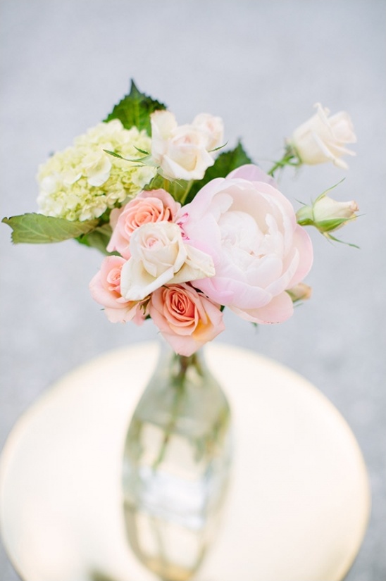 Pale pink flower arrangement in glass vase on gold table