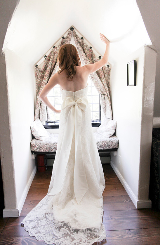 Bride in wedding dress looks out window, ready to say I do