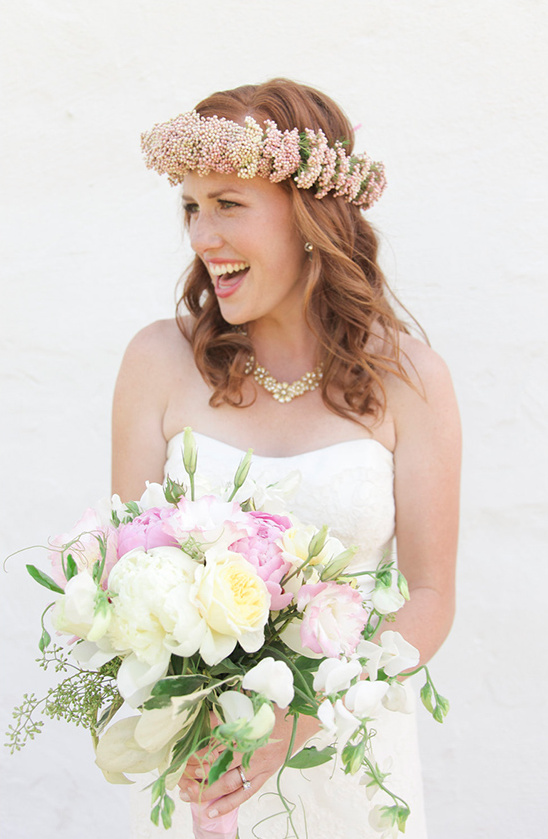 Beautiful bride with a floral crown smiles holding wedding bouquet